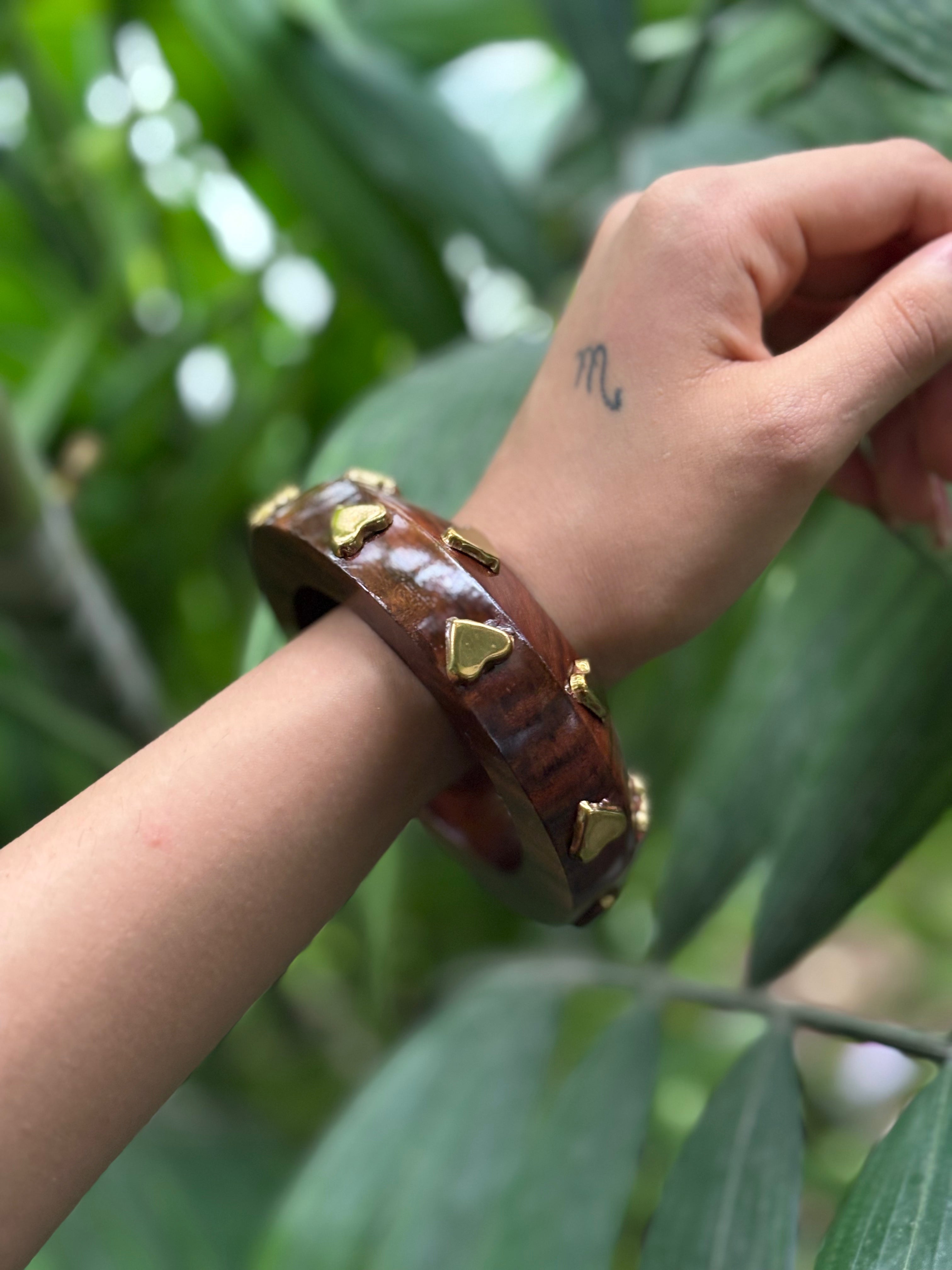 Close-up of golden heart motif on wooden bangle