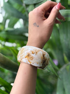 Close-up of white resin bangle with brown veining