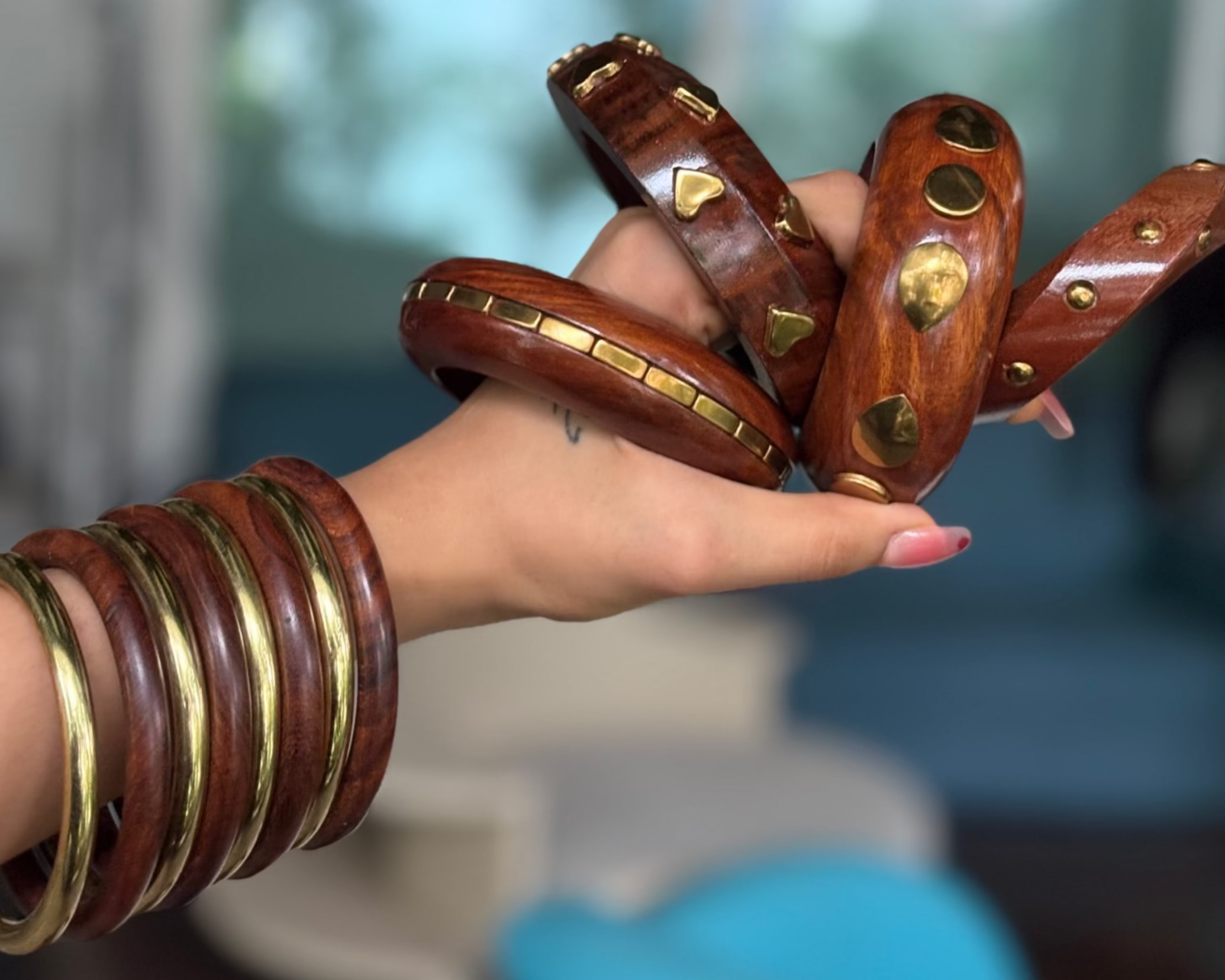 Hand wearing multiple wooden bangles with a blurred indoor background